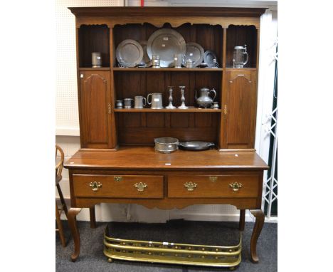 A mid-20th century oak dresser, ogee cornice over shaped frieze, two central shelves flanked by two cupboard doors both enclo