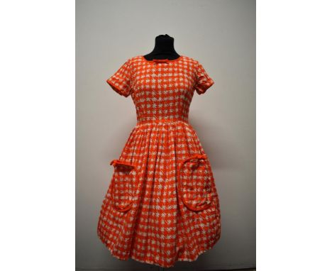 A textured medium weight cotton 1950s day dress, having orange and white dog tooth pattern, patch pockets to front with bows 