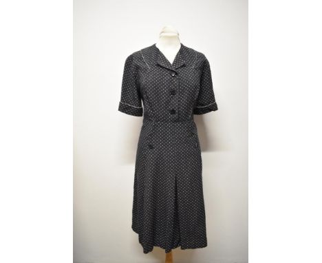 A dark navy blue medium weight cotton day dress with white polka dots, having piped detailing in white to bodice, button down