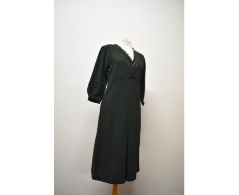 A 1930s bottle green day dress, having ladder work to sleeves and bodice, with cream twist detail to V shaped neckline.