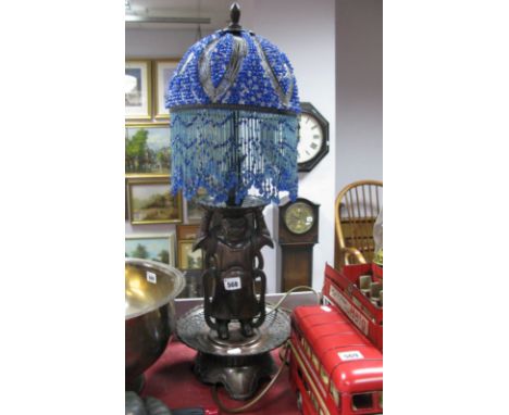 An Oriental Bronzed Metal Lamp, the base as a male figure, with tasseled beaded shade.