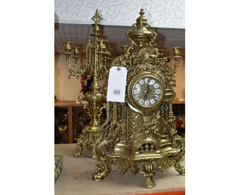 A BRASS FRANZ HERMLE CLOCK GARNITURE, the clock having a chapter ring inset with enamel Roman Numerals, the case is Rococo in