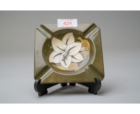 A ceramic ashtray by Moorcroft being stamped to reverse having a green glaze with the Bermuda Lilly design 1973 - 1975 approx