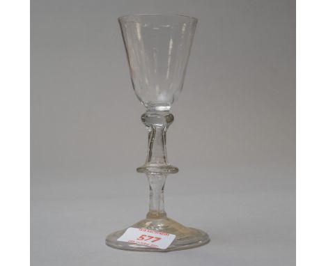 An early 18th century wine glass with folded foot and flat knop hollow stem tear with basal knop to base on plain bowl
Fair c