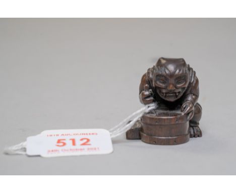 A traditional Japanese Netsuke or Netsky of a Demon or Oni carved in an exotic hardwood and bearing character seal mark to ba