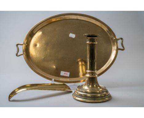 A vintage oval brass tray having handles to sides, a brass shoe horn and a brass candle stick holder.