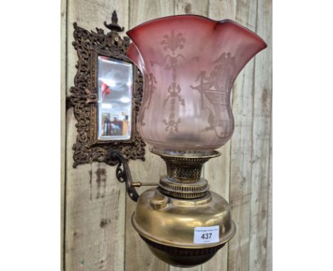 19th century ornate brass wall mirror with bracket holding a paraffin lamp. Lamp designed with acid etched pink glass shade. 