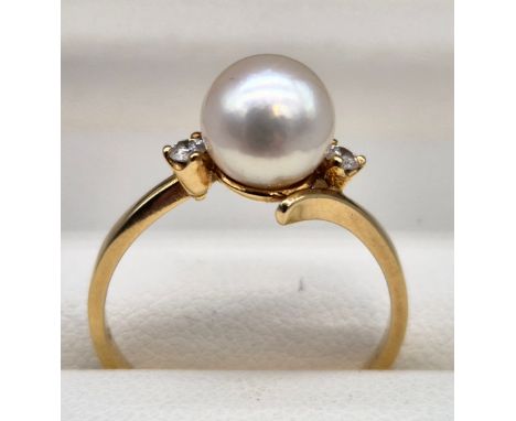 18ct yellow gold ring set with a single pearl off set with a single round cut diamond to each shoulder. [Ring size M] [2.41Gr