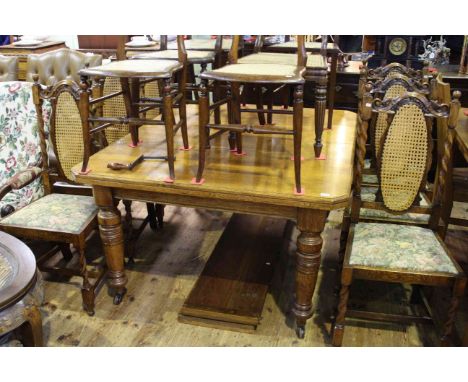 Early 20th Century oak extending dining table, two leaves and winder together with seven cane panel backed dining chairs