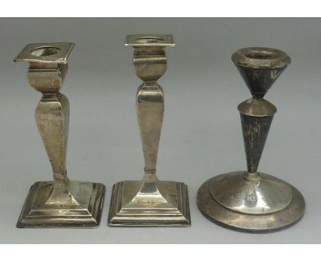 A pair of silver candlesticks, a/f, and one other silver candlestick, height of pair 12.5cm