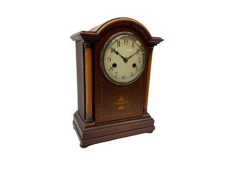An early 20th century mantle clock in a mahogany case with a break arch pediment, supported by two circular wooden columns wi