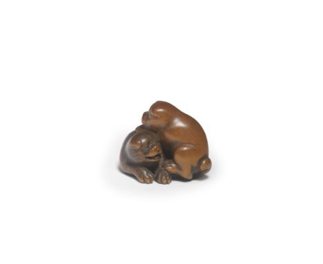 A WOOD NETSUKE OF TWO PUPPIESBy Masanao, Ise, Yamada, Edo period (1615-1868), mid-19th century One lifting itself onto the ot