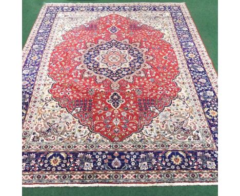 A Persian Tabriz carpet, with a central medallion and foliate motifs, on a red field, 360 x 255cm