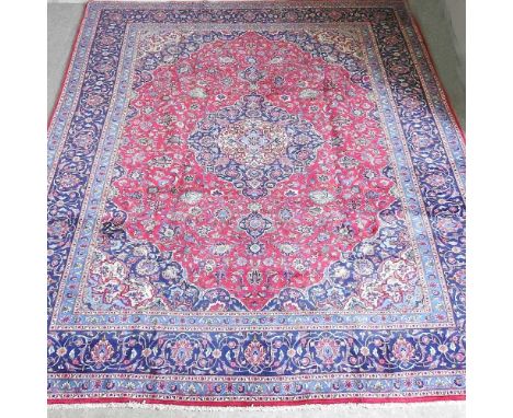A large Persian Meshed carpet, with all over foliate designs, on a red field, 400 x 300cm