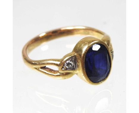 A sapphire and diamond set three stone ring, the central collet set stone, flanked by diamond shoulders, unmarked, 5.4g, size