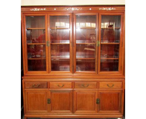 A Chinese hard wood and mother of pearl inlaid display cabinet, the pediment above two pairs of glazed doors enclosing six gl