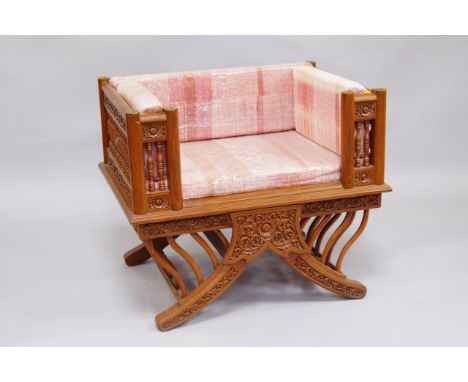 A Thai hardwood throne chair, the sides with bobbin turned and floral carved panelling, drop in cushions, raised on sabre leg