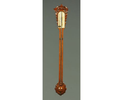 A Victorian oak stick barometer, with exposed tube and carved head and foot. CONDITION REPORT: The dial is faded and worn.  T