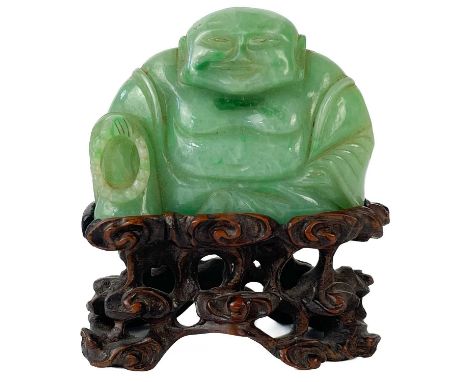 A Chinese green jade small carving of a seated Buddha with prayer beads. On original carved wood stand, height of jade 31mm, 