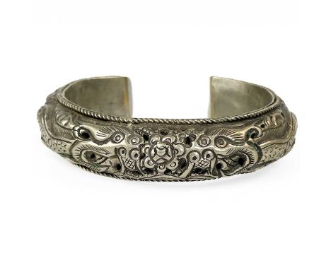 A Chinese silver bangle, early 20th century. Decorated with dragons chasing the flaming pearl, 7.5 x 9cm.