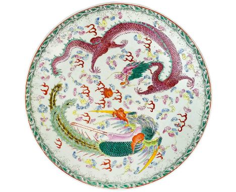 A Chinese famille verte porcelain charger, Guangxu period or later. Decorated with a dragon and phoenix chasing the flaming p