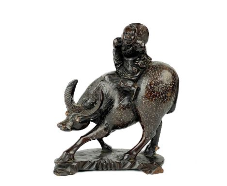 A Chinese carved wood model of a buffalo, circa 1900. With a figure on his back, silver wire inlay, height 27cm, width 20cm, 