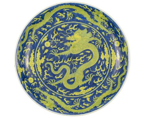 A Chinese porcelain dragon dish, Qianlong mark and period. Under-glazed blue and yellow-enamelled, the centre painted with a 