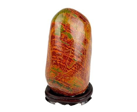 A Chinese mottled green hardstone boulder, mid 20th century. On wooden stand, total height 25cm, width 13cm, depth 10cm.