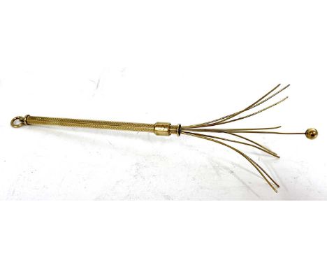 A 9ct gold swizzel stick cocktail stirer, the hexagonal barrel with engine turned decoration, and sliding mechanism suspended