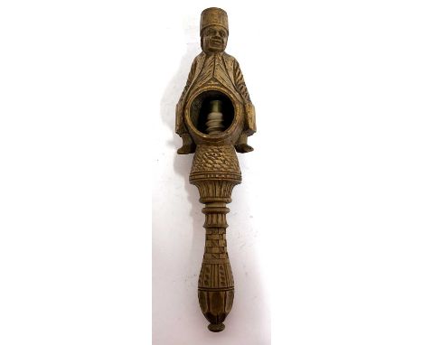 An antique treen box wood nut cracker, a carved figure sitting astride a barrel with screw handle, 23cm long