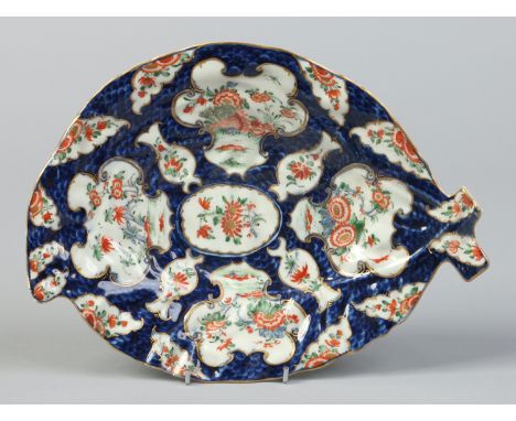 A Worcester leaf moulded dish. Scale blue ground, with gilt scrolling cartouches painted with Kakiemon flowers, c1770, 26cm. 