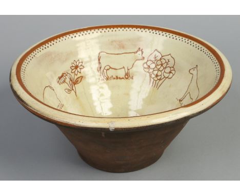 A terracotta pancheon or dairy bowl. With cream coloured glaze having sgraffito decoration depicting a cow, hose, pig, dog an