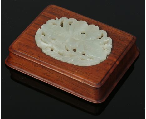 A 19th century Chinese carved hardwood scroll weight set with a pierced celadon jade carving of a peony rose, 8.5cm wide.    