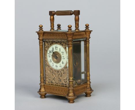 A late 19th century French brass carriage clock. With fluted column supports and having gilt mask adorned with scrolls, 16cm.
