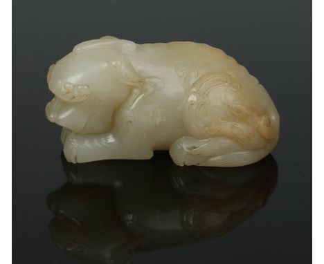 A Chinese Qing dynasty carved celadon jade carving of a recumbent one horned beast. Its head bowed and laying upon its front 