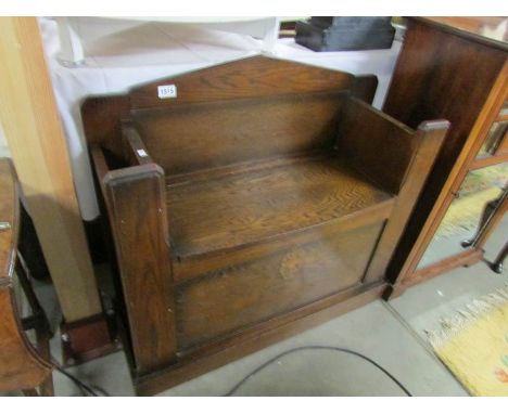 An oak settle incorporating umbrella and stick stand.