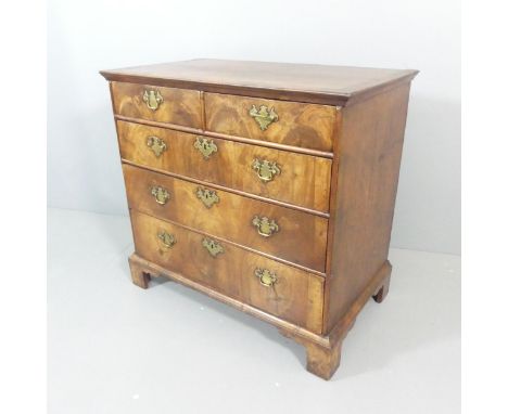 A Georgian crossbanded mahogany chest of two short and three long drawers, with flame veneered drawer fronts and raised on br