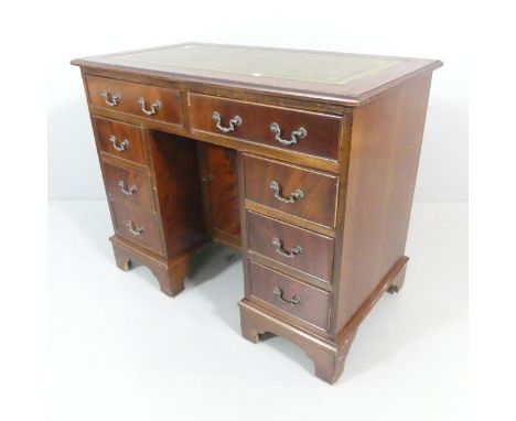 A reproduction Georgian style kneehole writing desk, with tooled and embossed green leather skiver, eight drawers, central cu
