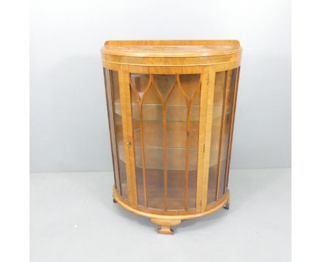 A 1930s walnut bow-front display cabinet, with single lattice glazed door, two glass shelves and bracket feet. 86x120x36cm. 