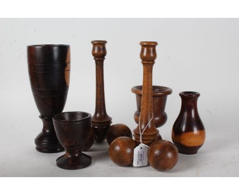 Collection of treen, to include two candlestick with cricket ball type feet, a tall lignum vitae vase, two lignum vitae goble