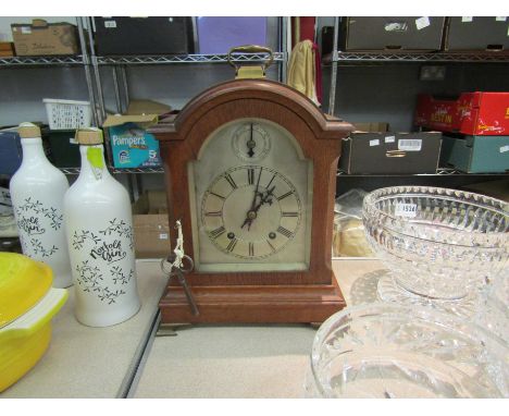 An oak cased bracket clock with Roman numerated chapter ring, key and pendulum