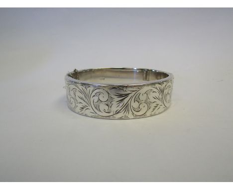 A silver stiff hinge bangle with engraved foliate design, hall marked Birmingham    