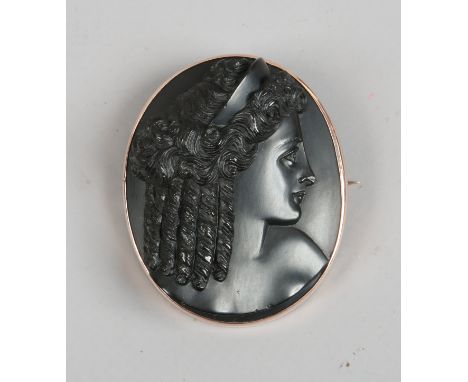 A gold mounted carved jet cameo brooch depicting a profile portrait of a maiden, signed S. Speedy.