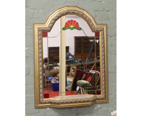 A gilt framed arch top mirror with leaded and stained decoration and shelf.