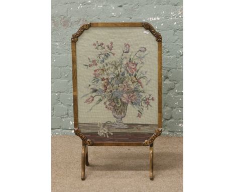 A carved mahogany folding firescreen set with woolwork upholstery.