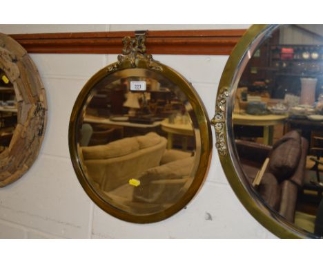 A circular brass and bevel edged wall mirror with ribbon tied decoration
