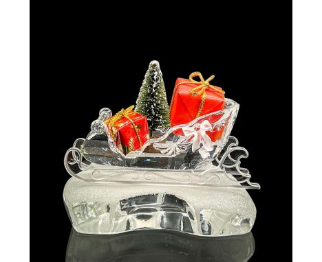 Clear crystal figure of a sleigh with two wrapped gifts and a tree inside. Swarovski mark. Retired; part of the Exquisite Acc