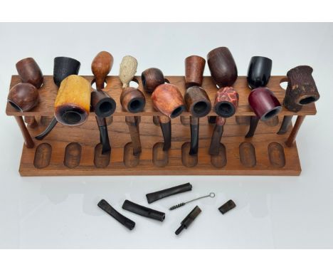 Numerous pipes and a wooden pipe holder. Pipes include Colonel Henry Fraser Lovat, Celebra Real Briar, Signature, Smokecraft 