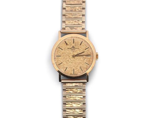 A Baume &amp; Mercier manual wind 18ct gold watch reference 35130, serial No. 957854. Gold textured dial on a hallmarked 9ct 
