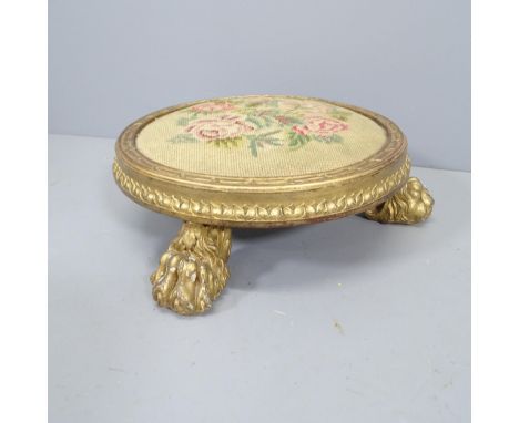 A Georgian tapestry-topped footstool, with gilded wood surround and lion paw feet, diameter approx 46cmSome chips to paw feet